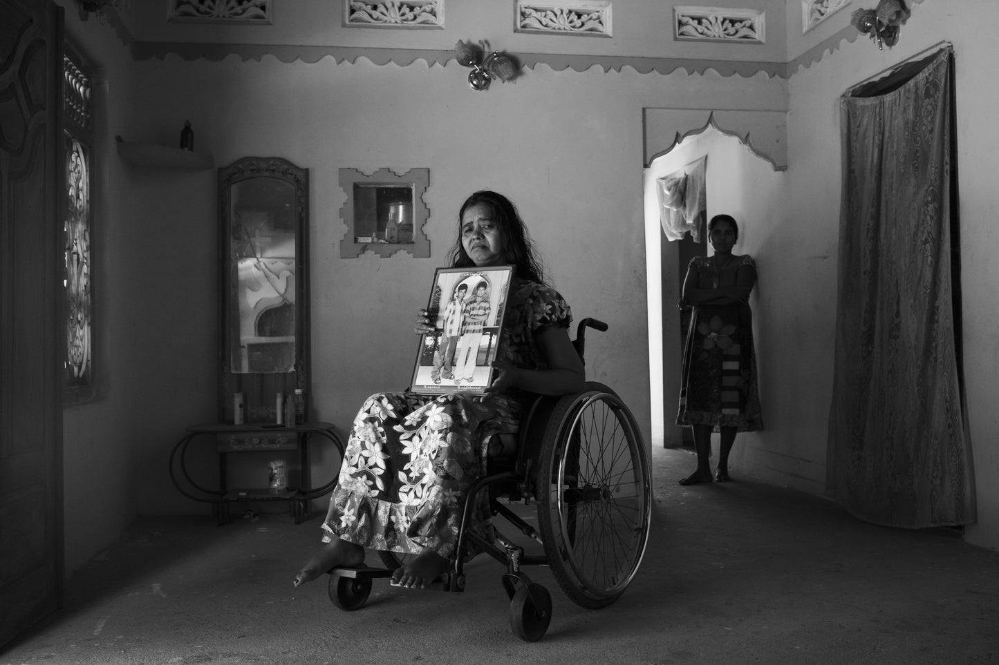 A woman injured in Sri Lanka's civil war holds a photograph of two sons killed in the conflict