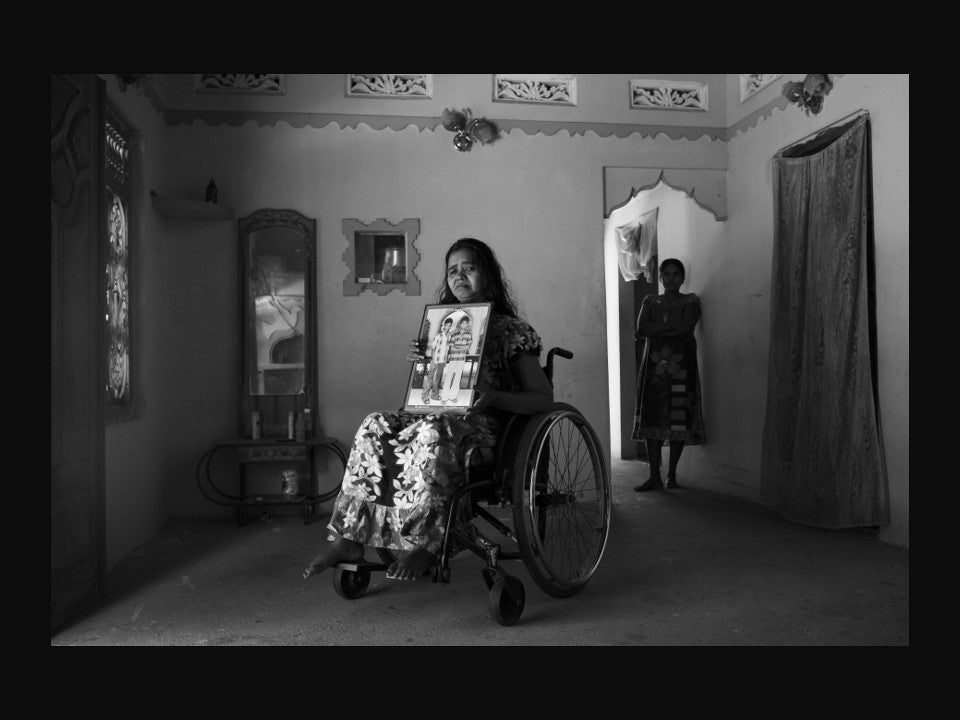 A woman injured in Sri Lanka's civil war holds a photograph of two sons killed in the conflict
